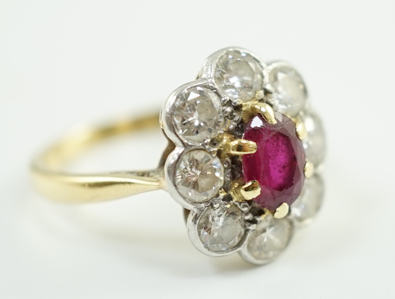 An 18ct gold, claw set single stone ruby and eight stone collet set diamond oval cluster ring